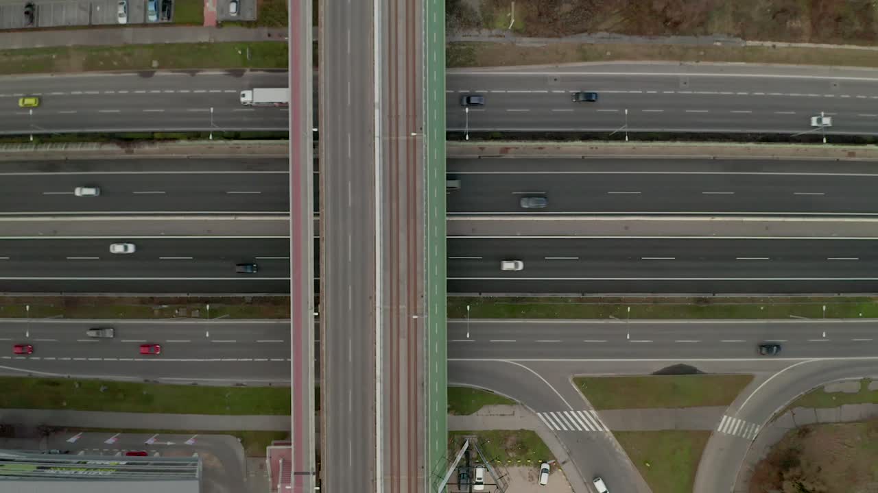 Aerial slowly ascending drone footage of a highway full of moving cars.