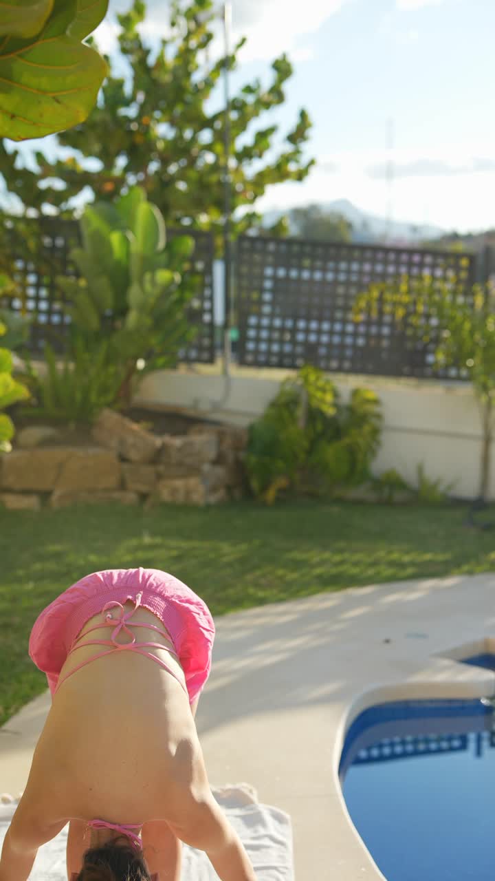 mujer practicando yoga y ejercicios de tabla junto a la piscina