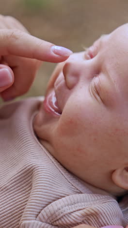 mom's hand touches baby's nose and the kid smiles. loving mother touching her child's face tenderly. close up. vertical video