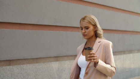 vista de cerca de una mujer caminando sosteniendo café en la calle