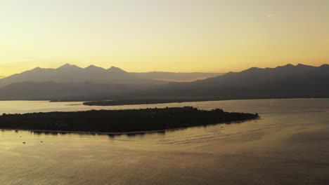 Islas-Gili,-Hermoso-Amanecer-Brumoso-Sobre-Las-Tranquilas-Aguas-Del-Mar,-Pequeñas-Islas-Y-Montañas-En-El-Fondo