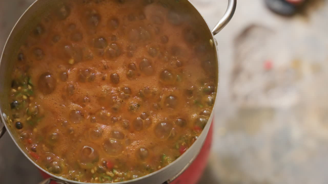 Tangan menambahkan bawang putih ke sup yang mendidih di panci, close-up jari-jari memisahkan siung dan menaburkan bumbu ke dalam kuah yang mendidih, masakan rumahan yang terasa, gerakan koki yang fokus, aroma gurih yang hangat.