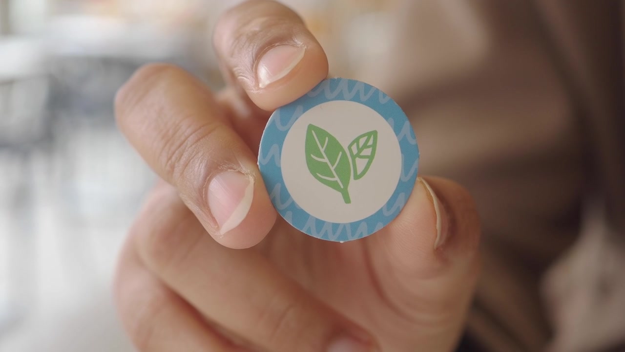 Close-up de Mão Segurando Adesivo de Folha Ecológico