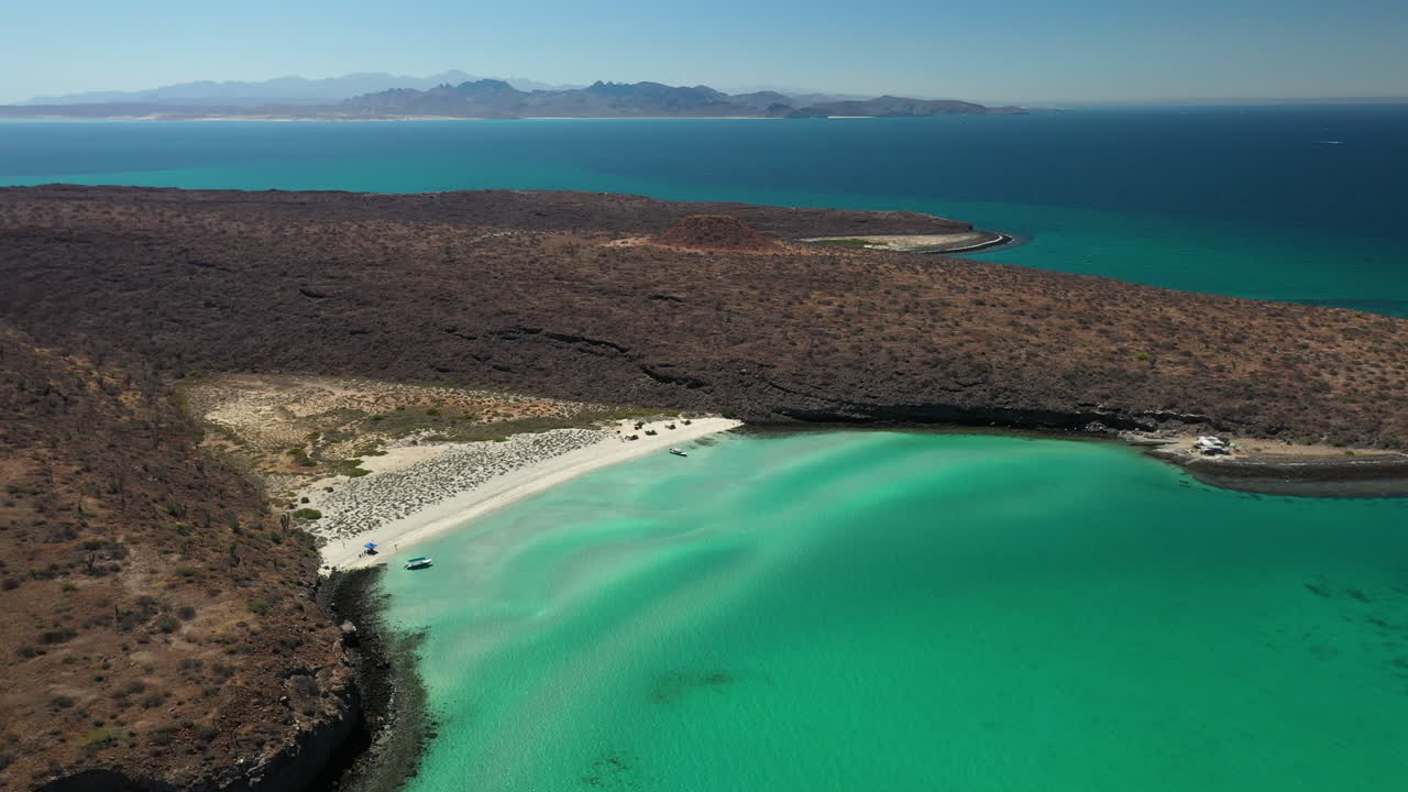 발란드라 해변의 영화 같은 드론 샷, 붉은 언덕과 청록색 바다 위를 지나 와이드샷 회전