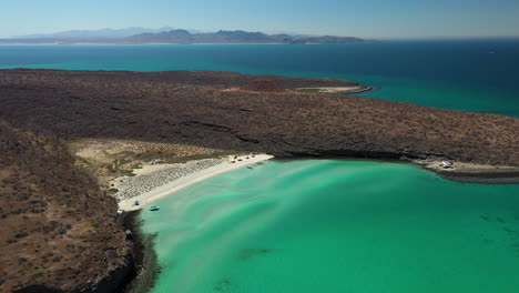 Cinematic-drone-shot-of-Balandra-Beach,-passing-over-the-red-hills-and-turquoise-waters,-rotating-wide-shot