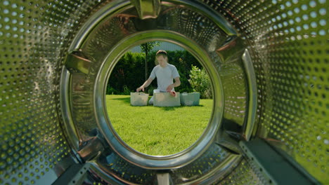 man loading clothes into a washing machine in a garden