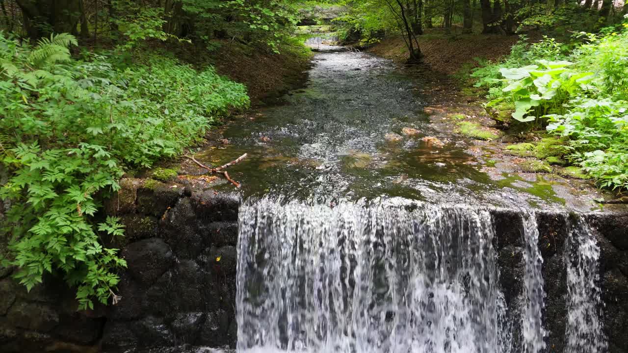 Hiking trail through lush forest leading to Sutovsky waterfall in Mala Fatra, Slovakia. Aerial view of small waterfall along the path. Scenic nature, perfect for travel and outdoor adventure themes