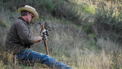 cowboy hunter setting up wildlife game camera on post