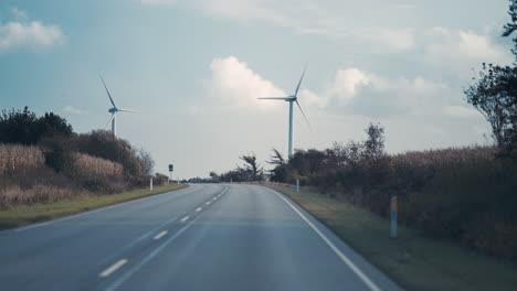 wind turbines stand on both sides of the two-lane road