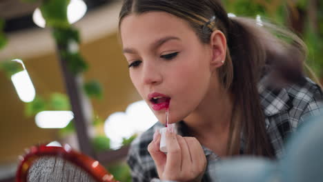 closeup view of young lady applying lipstick in front of mirror, focus on lip makeup process, enhancing lips with vibrant red color while background remains blurred