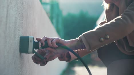 Tracking-shot-of-a-female-plugging-in-an-electricity-cord-into-a-power-outlet