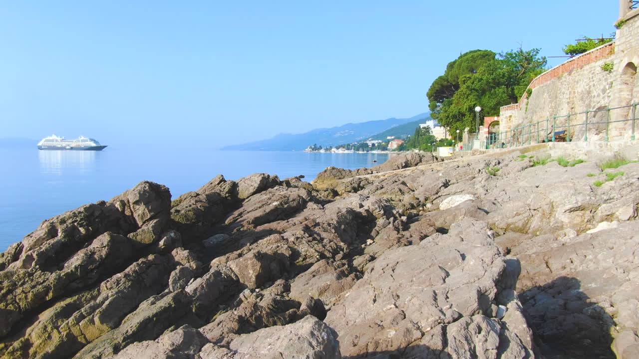 바다를 항해하고 해안 가까이 오는 대형 선박을 볼 수 있는 바다 해안의 바위 위로 비행