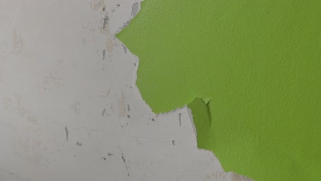 Daueraufnahme-Eines-Mannes,-Der-Grüne-Farbe-Von-Einer-Wand-Abkratzt,-Die-Mit-Renovierungsarbeiten-Beschäftigt-Ist