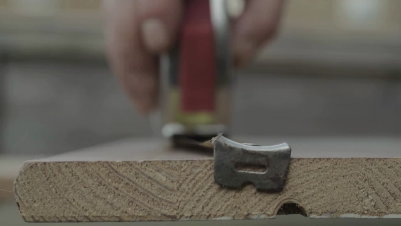 Workman hand using metal tape measure to measure piece of wood