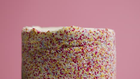 close up studio shot of revolving birthday cake covered with hundreds and thousands decorations 10