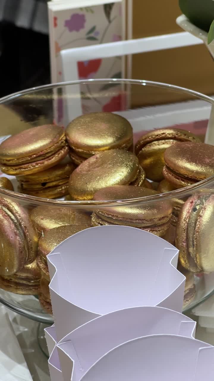 Golden macaron confections in confectionery glass bowl, vertical shot