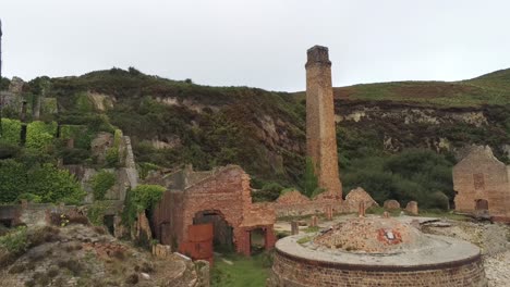 Porth-Wen-aerial-pullback-view-abandoned-Victorian-industrial-brickwork-factory-remains-on-Anglesey-eroded-coastline