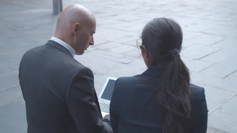 rückansicht von geschäftskollegen, die sich unterhalten und gemeinsam an einem projekt arbeiten, während sie draußen im bürogebäude sitzen