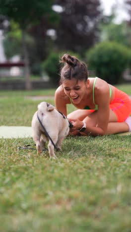 woman playing with a pug dog in a park