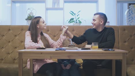 man-and-pretty-lady-with-joined-hands-sit-in-restaurant