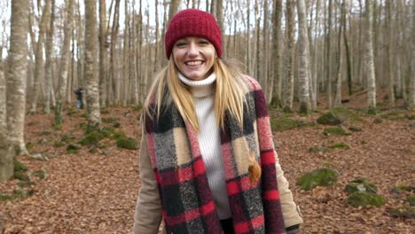 Young-smiling-happy-woman-throws-dry-leaves-towards-camera