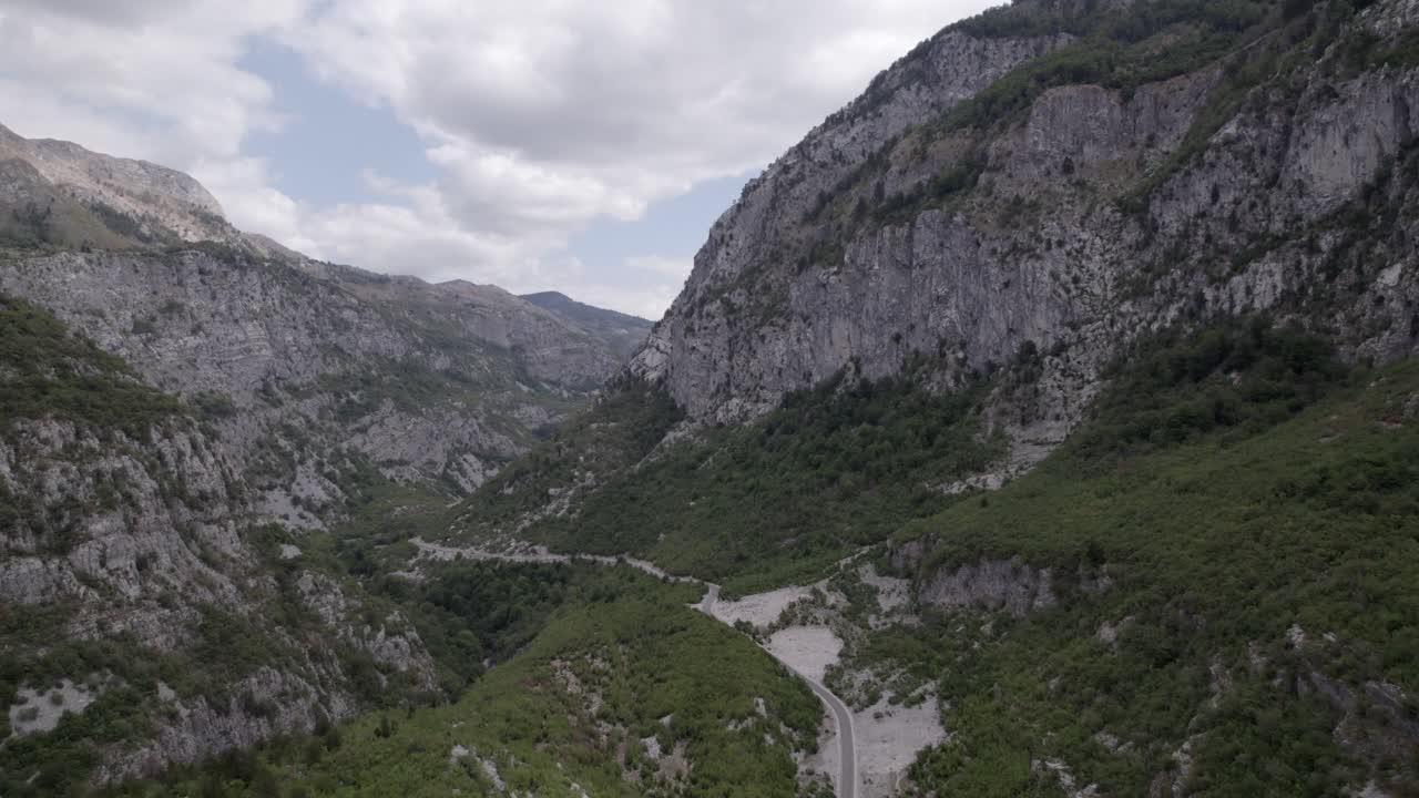 video de drones del avión frontal avanzando en la autopista sh20 en albania, a la altura de javor y mreg, camino de serpientes, se pueden ver pequeñas casas de la ciudad, cielo nublado