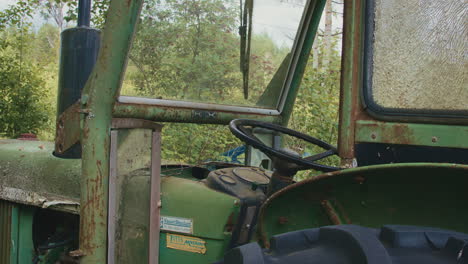 Detailed close-up of an old tractor's interior, featuring rusted metal and shattered windows.