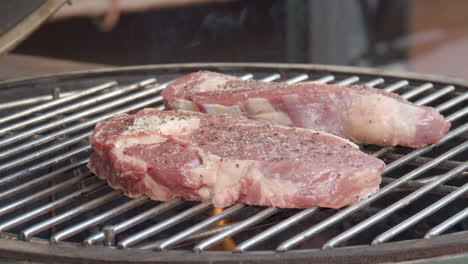 rib eye steaks on flaming and smoking barbecue