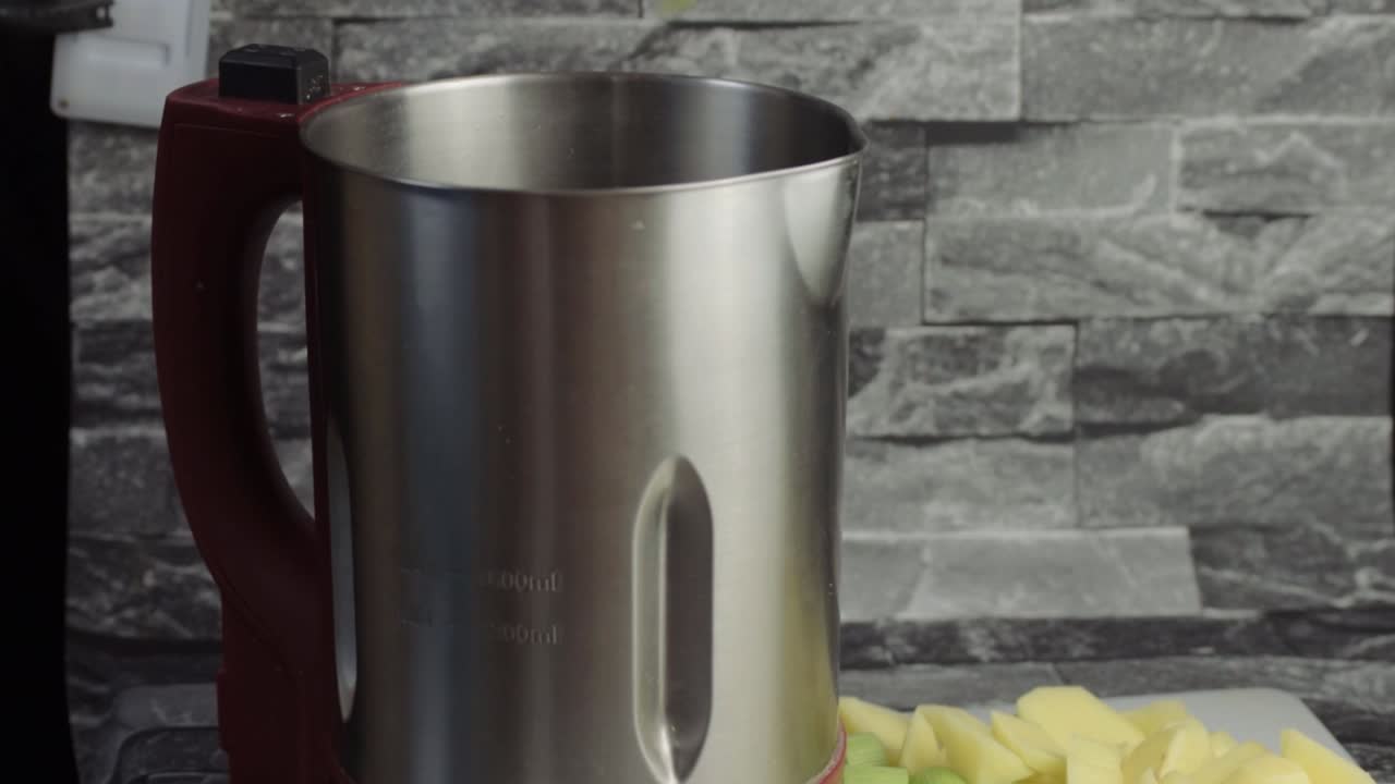 Hand putting ingredients into a soup maker wide shot