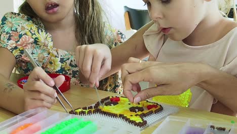 two girls making pixel art with beads