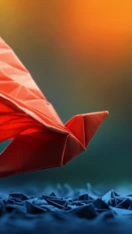 origami bird soaring above blue paper. a vibrant red origami bird appears to fly over a textured blue paper surface, highlighted by soft, glowing light.