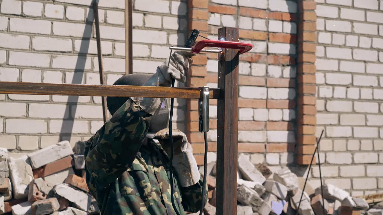 장인 은 시골 집 의 미래 울타리 의 상단 부분 을 용접 한다