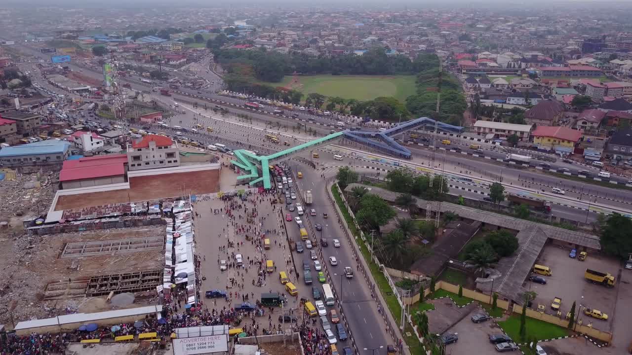 vista aérea de una carretera en lagos nigeria con una vista de un puente peatonal y coches y camiones ocupados moviéndose con atascos de tráfico