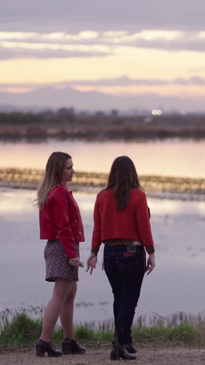 Two Women Walking by the Lake at Sunset