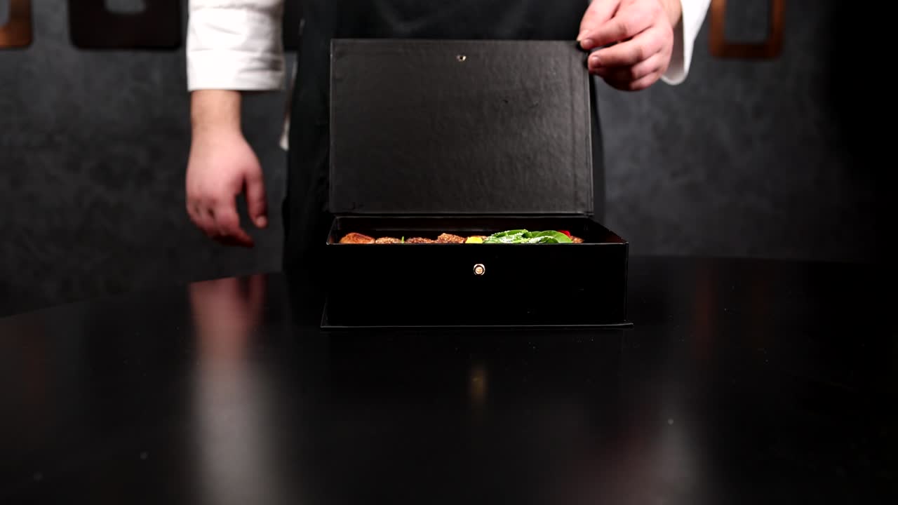 chef presentando un plato gourmet en una caja negra