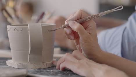 woman hands during painting on ceramic plates. potter workshop of making handcraft clay dishes. artist creates a beautiful pattern on earthenware in a pottery workshop. close-up slow motion