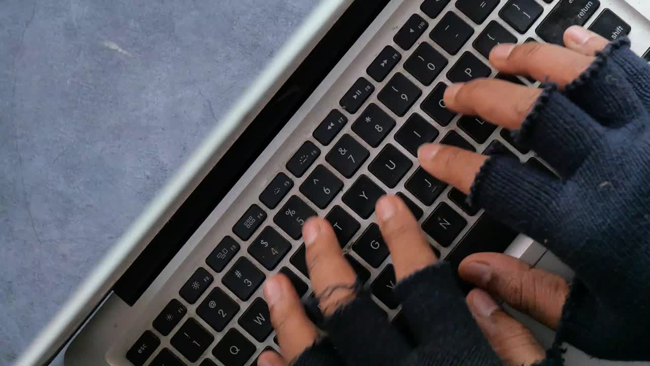 persona escribiendo en una computadora portátil con guantes