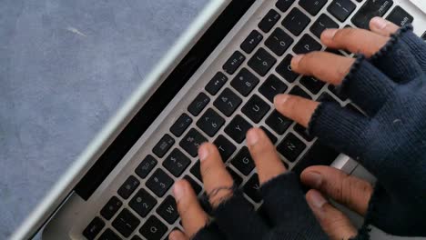 person typing on a laptop with gloves