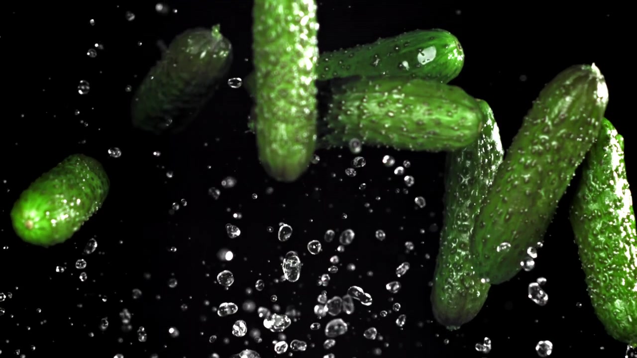 Fresh Green Cucumbers Falling with Water Drops in Slow Motion