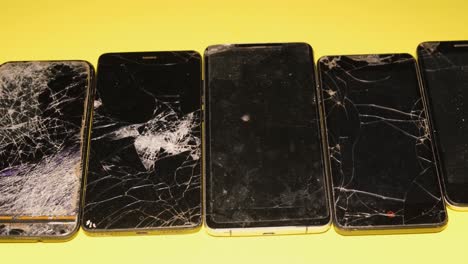 collection of broken smartphones with cracked screens
