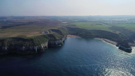 Beautiful-chalk-coastal-cliffs-at-low-tide,-with-visible-cracks-showing-in-the-cliff-faces