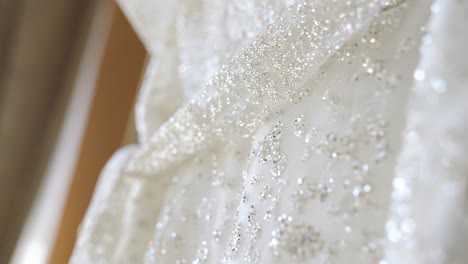 primer plano de los detalles del vestido blanco de una novia con lentejas de oro