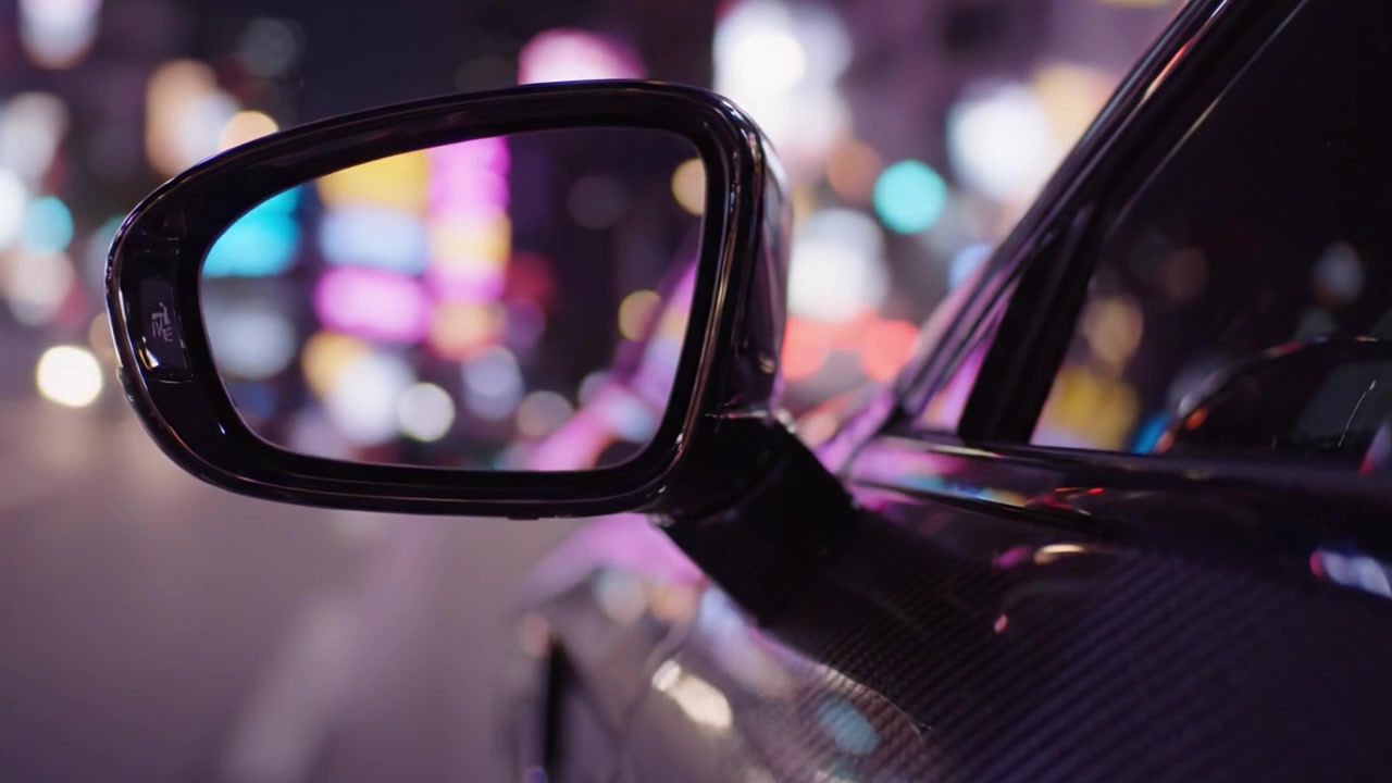 Un'affascinante scena urbana notturna con uno specchietto d'auto che riflette le luci vibranti della città, evidenziando la fusione di modernità e dinamismo in un'inquadratura artistica.