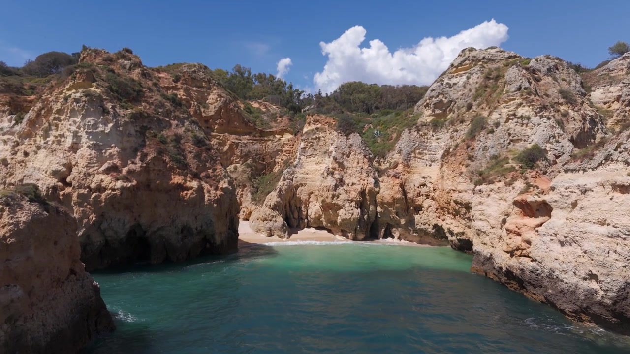 Ripresa drone in avvicinamento che rivela una spiaggia segreta e nascosta circondata da rocce, Algarve, Portogallo