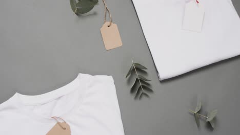 video of flat lay of white t shirts with tags and copy space on grey background