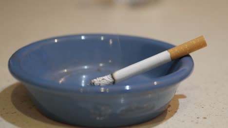 cigarette burning on blue ashtray, time lapse