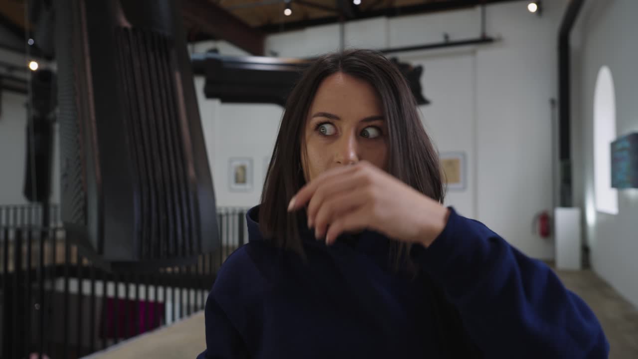 frustrada mujer morena arregla el cabello en la galería de arte david cerny, praga