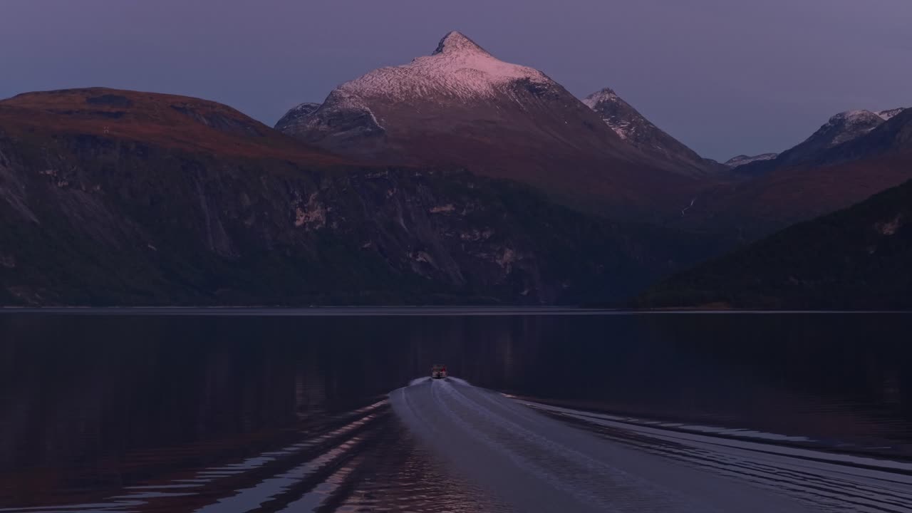 Motoscafo che scivola su acque illuminate dal tramonto in uno scenografico fiordo norvegese.