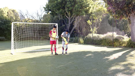 asian father and teenage son playing soccer together on sunny day, copy space