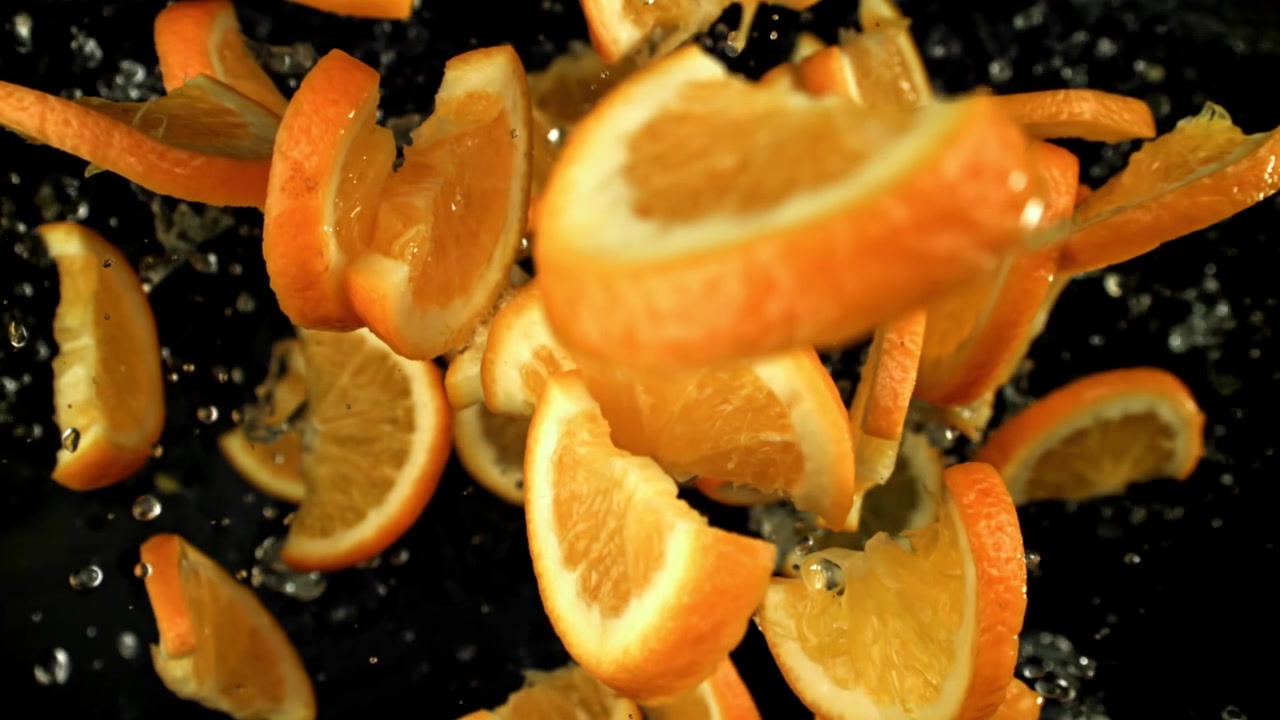 Super slow motion di fette d'arancia che cadono e schizzano nell'acqua